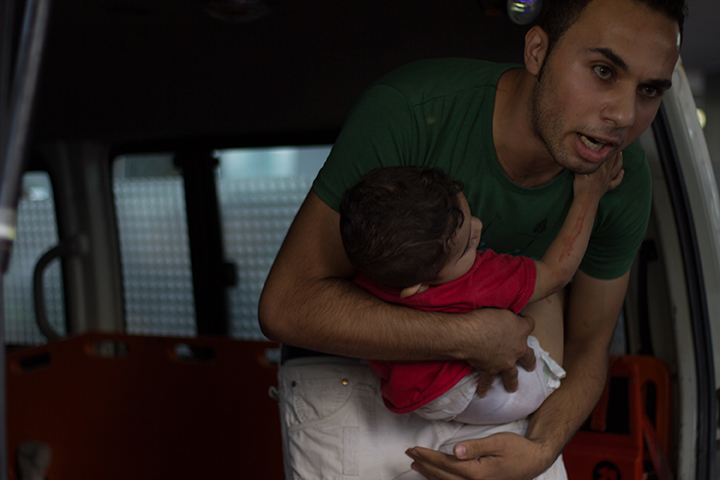Un palestinien tenant un bébé blessé lors des massacres de 2014_1