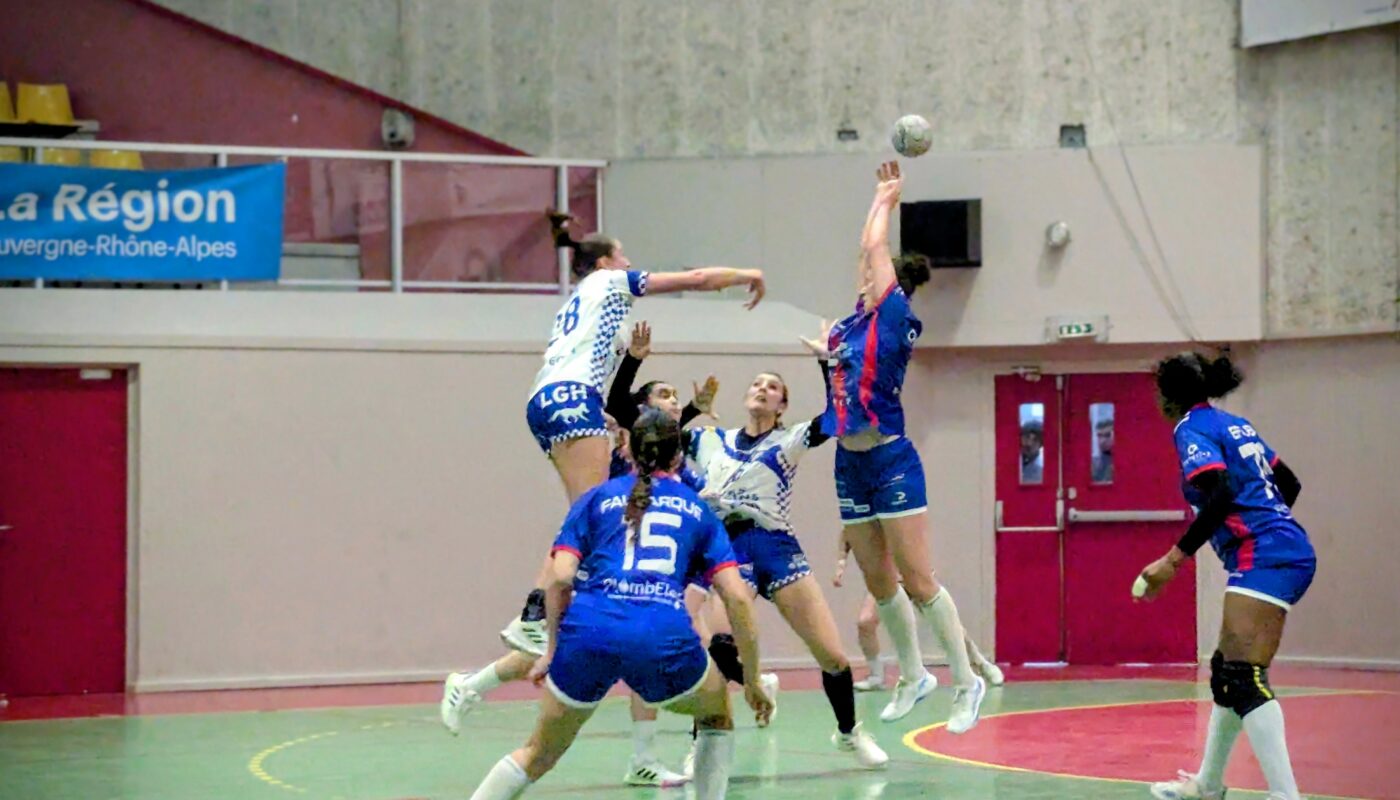 Match de handball en salle : plusieurs joueuses en tenue bleue (ASUL) et blanche (Bègles) sautent au centre du terrain pour intercepter ou lancer le ballon, tandis que leurs coéquipières se positionnent autour d’elles.